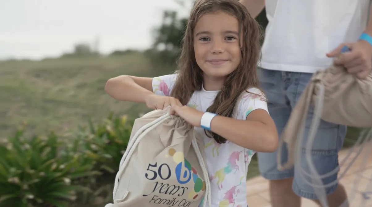 Niña sonriente sosteniendo una bolsa de tela conmemorativa del 50 aniversario del Family Day de Bioiberica durante el evento en Palafolls