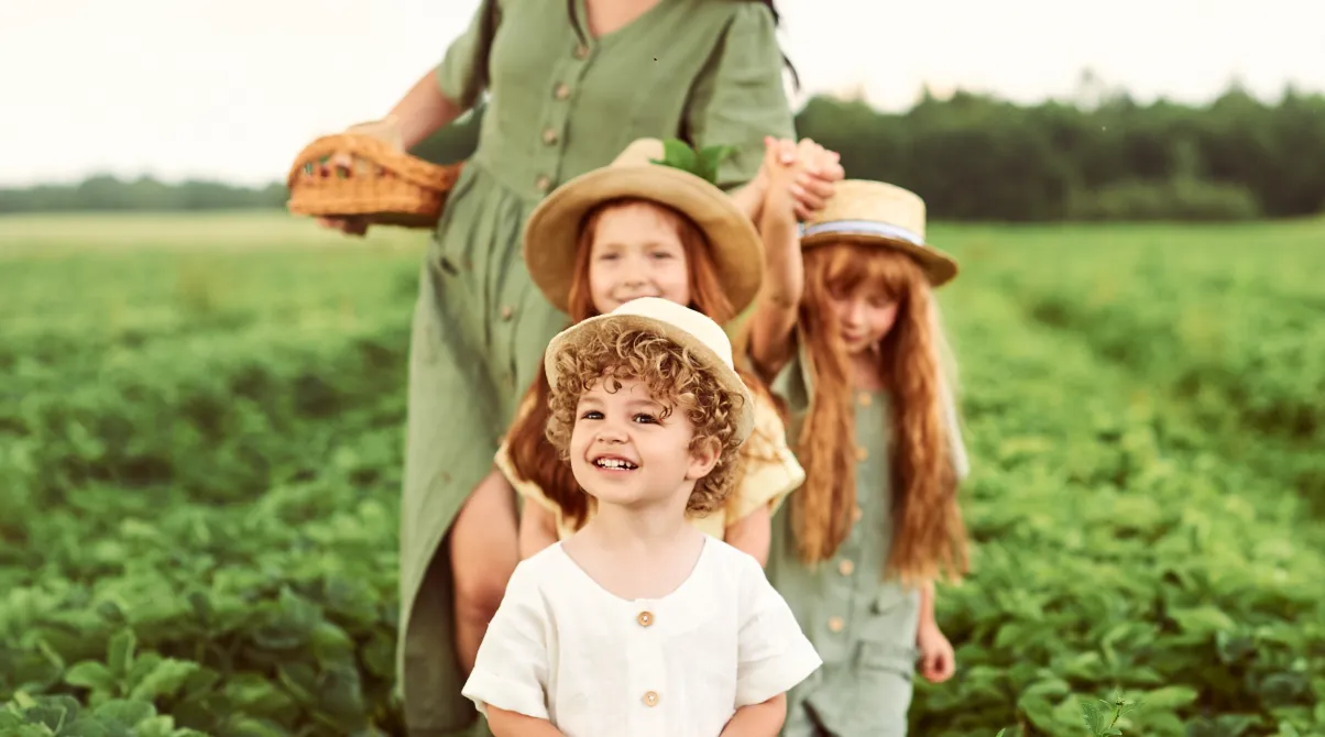 Mother with three children wearing hats in green crop field, representing sustainable agriculture and plant health