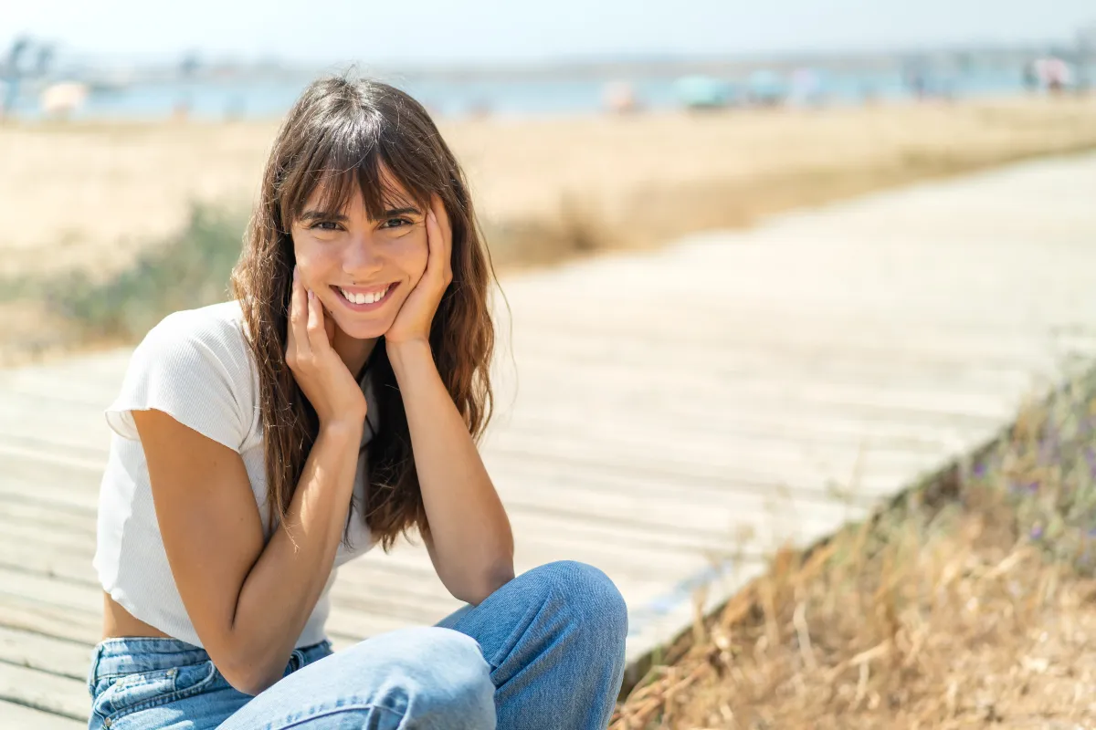 Mujer joven sonriente mostrando piel radiante y luminosa con efecto glow