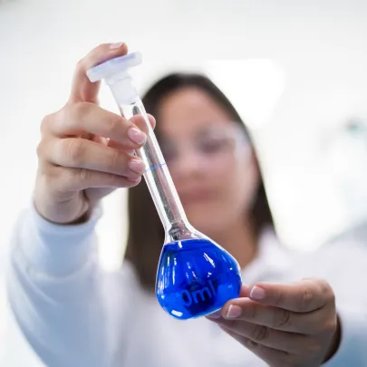 Scientist handling pipette with blue liquid in pharmaceutical laboratory