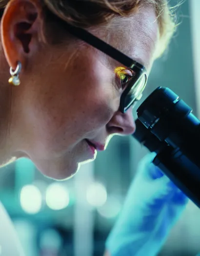 Female scientist examining samples under microscope in Bioiberica laboratory, representing clinical research behind Collavant n2